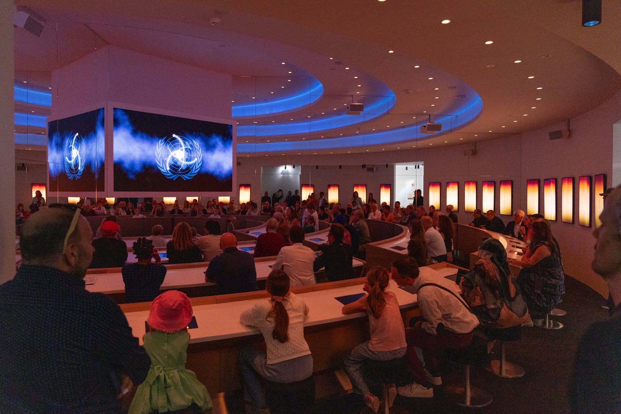 Visitors seated in the curved negotiation chamber of the Together experience, voting at kiosks.