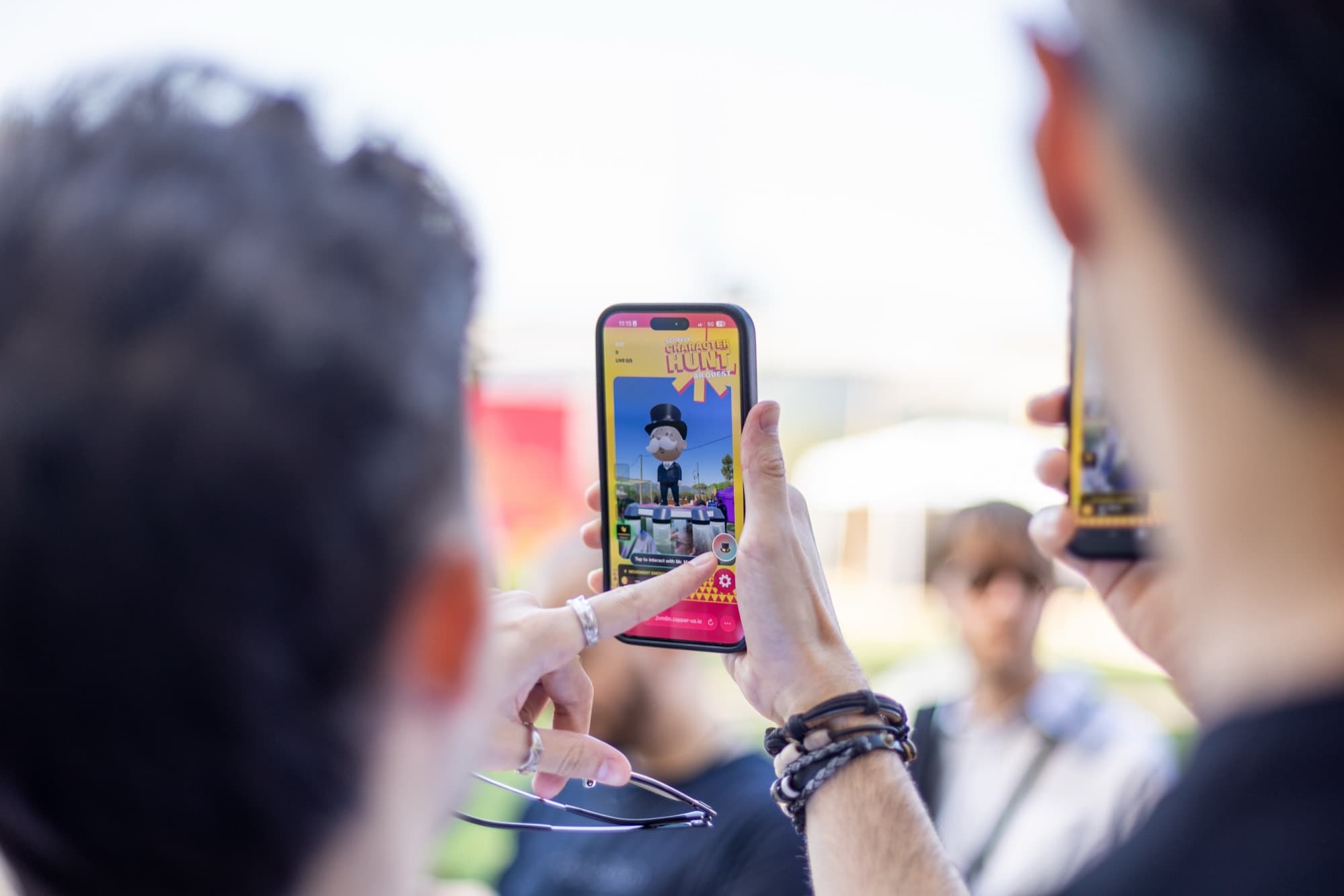 Close-up of hands holding a smartphone displaying a game character in browser AR outdoors.