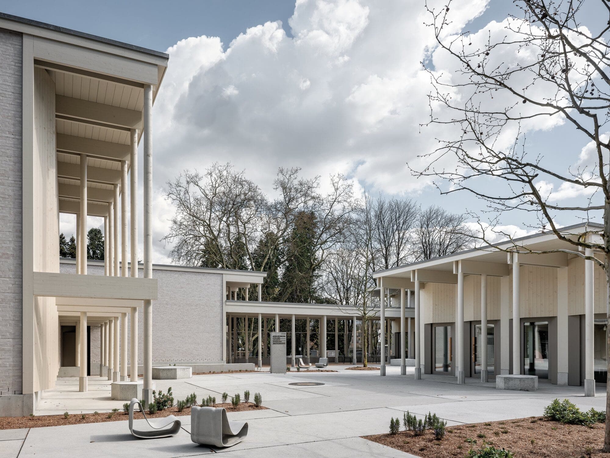 White colonnaded pavilions of the Portail des Nations among trees.